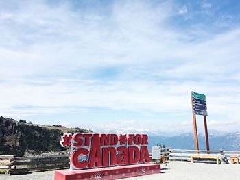 Information sign by road against sky