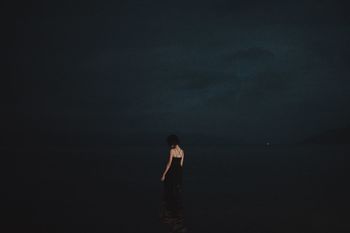 WOMAN STANDING ON BEACH AGAINST SEA AGAINST SKY