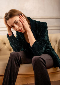 Portrait of young woman sitting on sofa at home