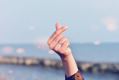 Cropped hand gesturing against sky