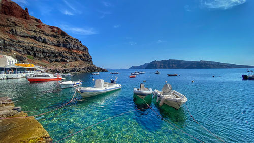 Boats moored in sea against blue sky