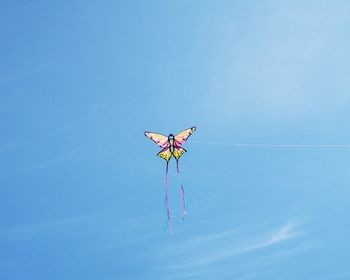 Low angle view of kite flying against clear blue sky