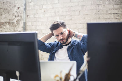 Serious young computer programmer looking at laptop while working in office