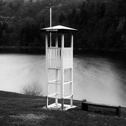 Built structure by calm lake against trees in forest