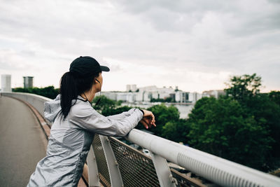 Sportswoman leaning on railing at footbridge in city