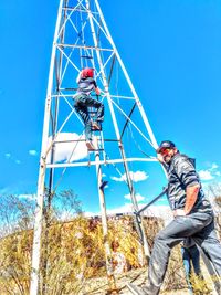 Low angle view of man standing against clear blue sky