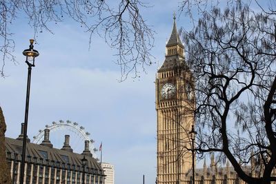 Low angle view of big ben and london eye against sky