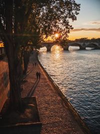 Bridge over river against sky at sunset