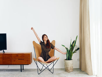 Young woman sitting on chair at home