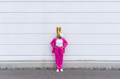 Full length of woman standing against pink wall