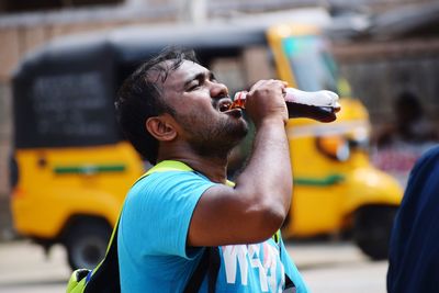 Man drinking drink from bottle in city