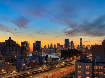 Illuminated buildings in city against sky during sunset