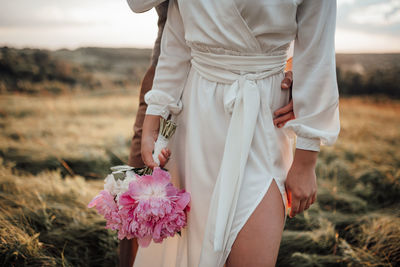 Midsection of woman holding umbrella standing on field