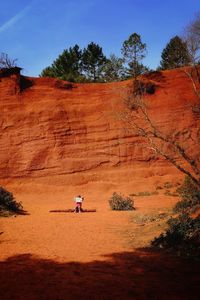 Girl with paper sitting on desert against rock formation