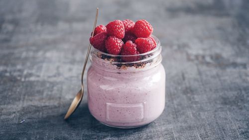 Close-up of smoothie with raspberries in container on table