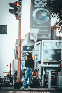 Full length portrait of young woman standing in city