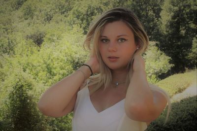 Portrait of beautiful young woman standing against trees