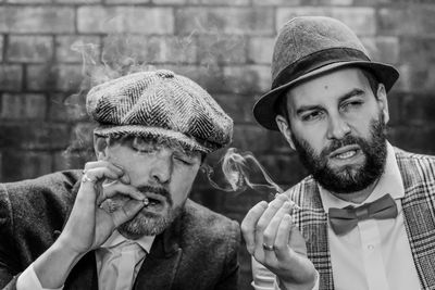 Close-up of men smoking cigarette against wall