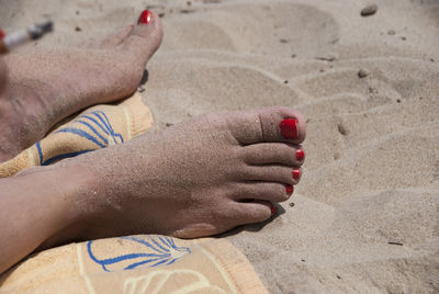 Low section of person relaxing on sand at beach