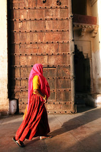 Side view of woman walking by wooden door