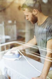 Side view of young man looking at camera