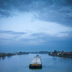 Sailboat sailing on river against sky