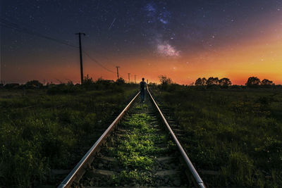 Man walking on railroad track at night