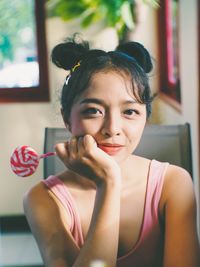 Portrait of smiling young woman holding lollipop