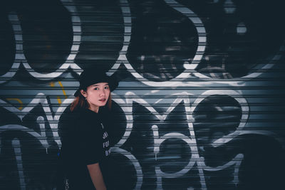 Full length of woman standing against graffiti wall