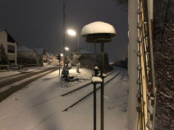 Street light on snow covered road against sky