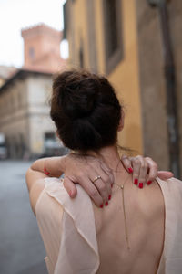 Rear view of woman standing against buildings in city