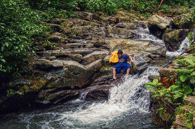 Rear view of man and woman standing on river in forest