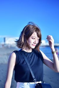 Young woman smiling against blue sky