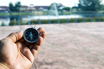 Cropped hand of person holding navigational compass at park