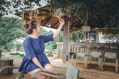 Woman taking selfie while sitting on chair