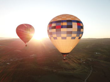 Hot air balloon flying over landscape against sky during sunset
