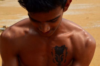 Close-up of young shirtless man standing outdoors