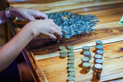 Cropped hand of woman counting coins while stacking on table