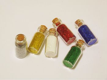 High angle view of multi colored sparkles in bottles on table