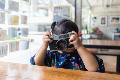 Girl with camera photographing in cafe