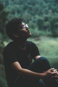 Young man looking away while sitting outdoors