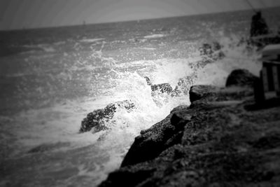 Sea waves rushing towards shore against sky