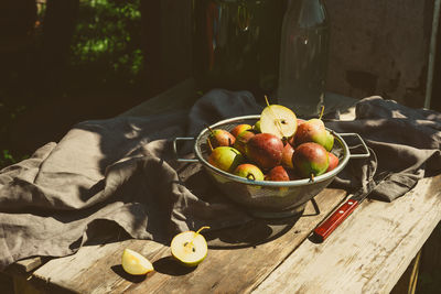 Many ripe pears in a colander on wooden garden table