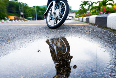 Motorcycle reflecting in puddle on road