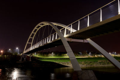 Bridge over river in city against sky at night