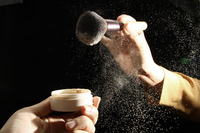 Midsection of person holding coffee cup against black background