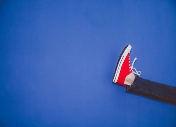 Low section of red shoes against clear blue sky