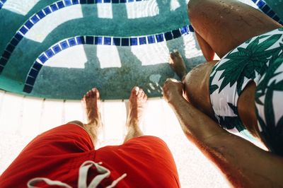 Low section of man standing by swimming pool