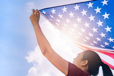 Low angle view of woman holding flag against sky