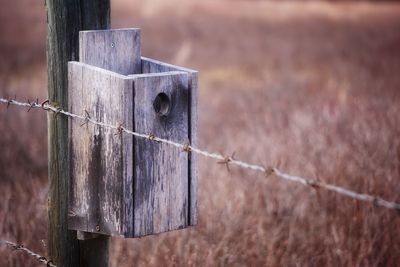 Wooden birdhouse on post by barbed wire